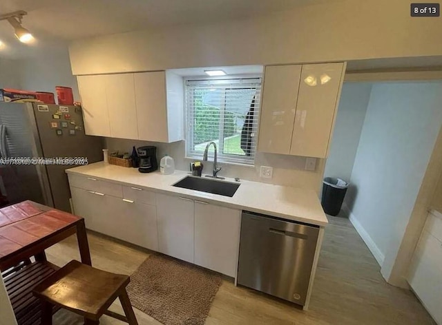 kitchen with dishwasher, modern cabinets, a sink, freestanding refrigerator, and white cabinetry