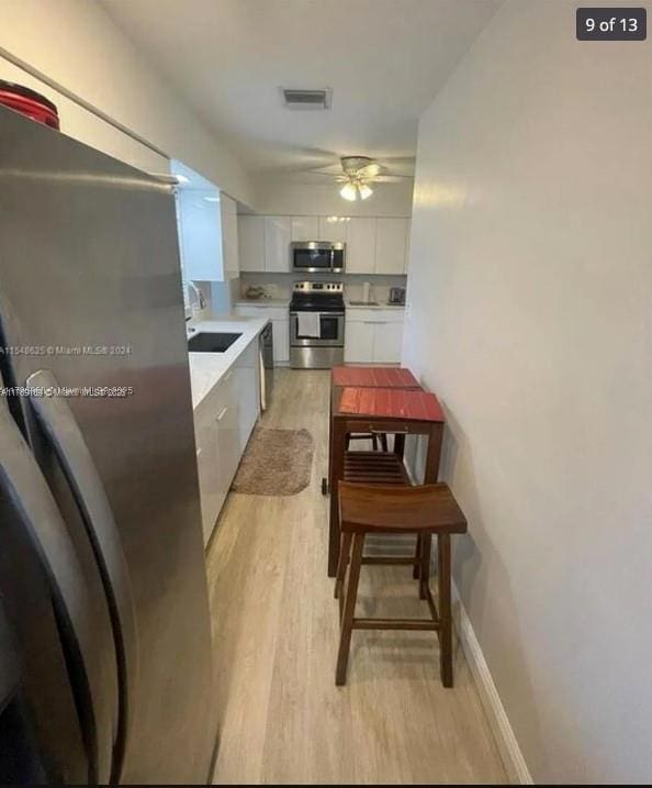 kitchen featuring modern cabinets, light wood finished floors, white cabinetry, appliances with stainless steel finishes, and visible vents