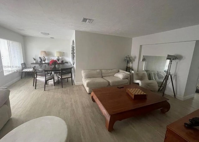 living room featuring baseboards, light wood-style flooring, and visible vents