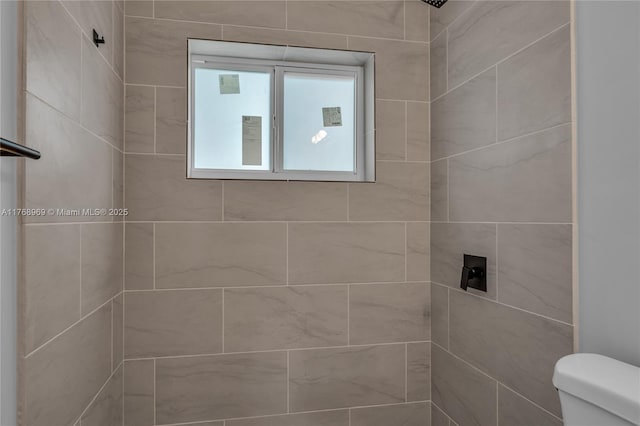 bathroom featuring toilet and a tile shower