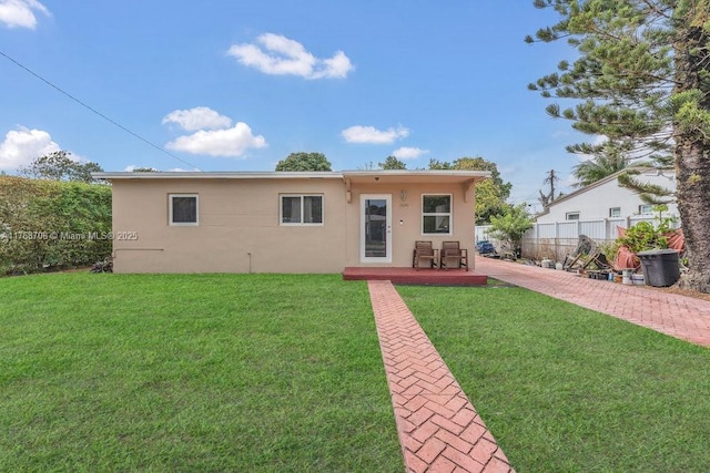 view of front facade featuring stucco siding, a patio, a front lawn, and fence
