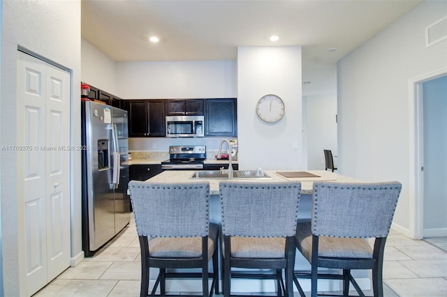 kitchen featuring a breakfast bar, light tile patterned floors, visible vents, stainless steel appliances, and a sink