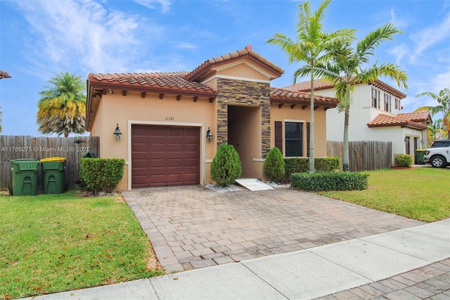 mediterranean / spanish house with a tile roof, decorative driveway, a garage, and stucco siding