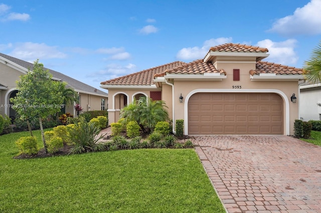 mediterranean / spanish-style house featuring a tiled roof, a garage, stucco siding, a front yard, and driveway