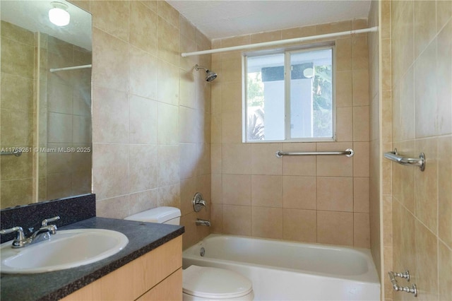 full bathroom featuring tile walls, toilet, vanity, and bathtub / shower combination