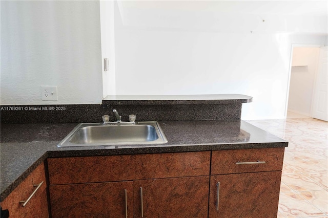 kitchen with a sink, dark countertops, and marble finish floor