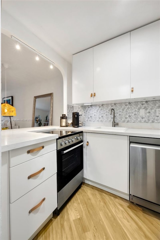 2899 Collins Ave Unit 1638, Miami Beach, FL 33140 - kitchen featuring appliances with stainless steel finishes, white cabinets, light wood-type flooring, and light countertops