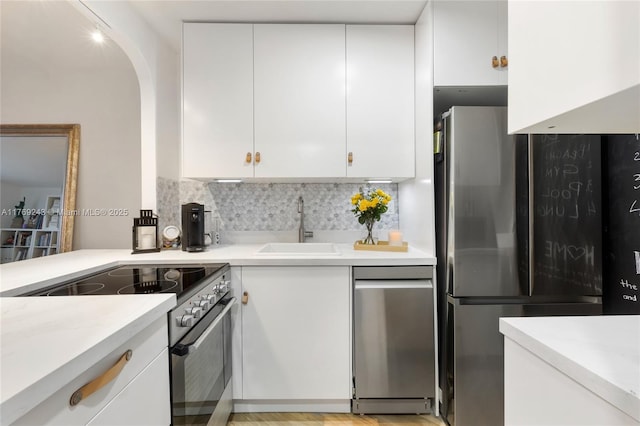 2899 Collins Ave Unit 1638, Miami Beach, FL 33140 - kitchen with stainless steel appliances, a sink, white cabinets, backsplash, and light countertops