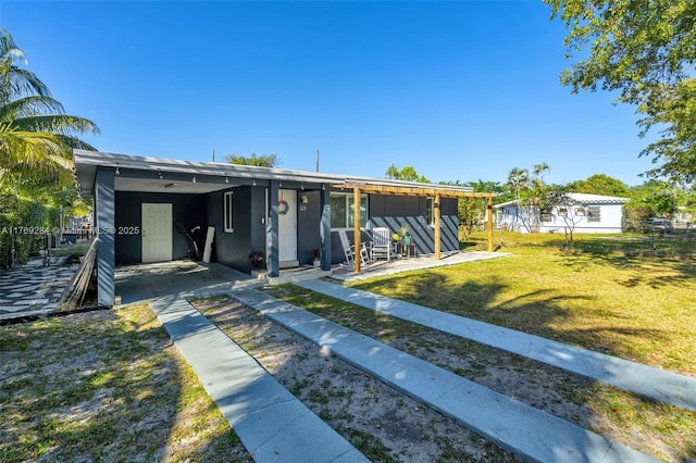 back of property with driveway, a carport, stucco siding, and a yard