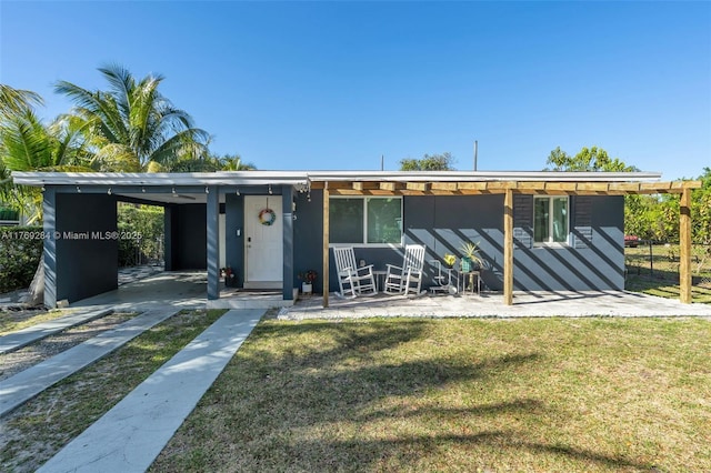 mid-century modern home featuring driveway, a front lawn, and a carport