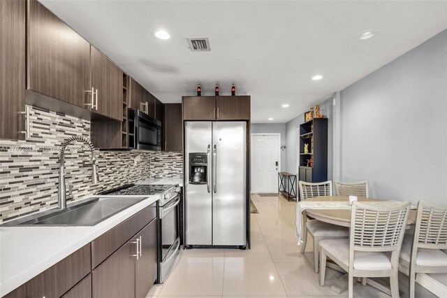 kitchen featuring light countertops, tasteful backsplash, light tile patterned flooring, visible vents, and appliances with stainless steel finishes