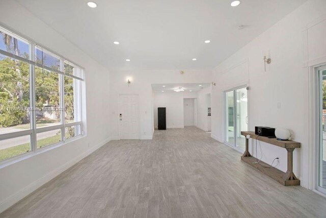 unfurnished living room with baseboards, recessed lighting, and light wood finished floors