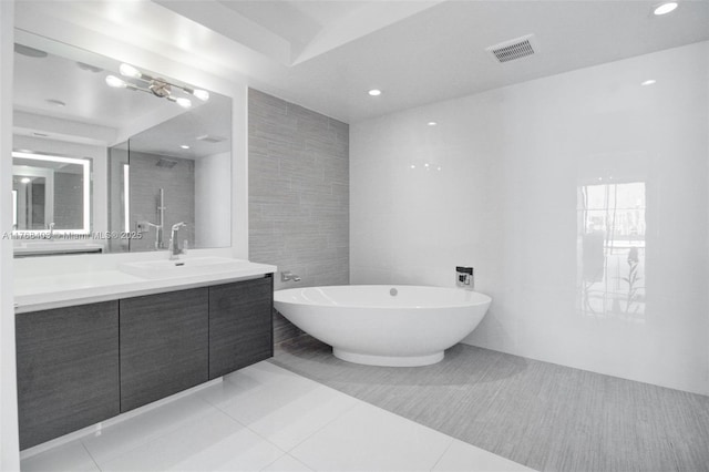 bathroom with tile patterned floors, vanity, tile walls, a soaking tub, and visible vents
