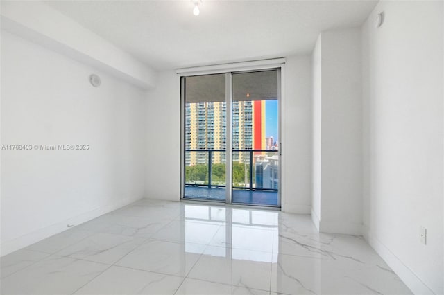 unfurnished room with baseboards, a wall of windows, and marble finish floor