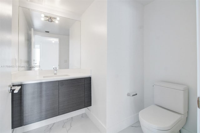 half bath with marble finish floor, toilet, vanity, and baseboards