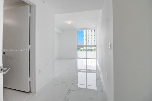 corridor featuring marble finish floor and baseboards