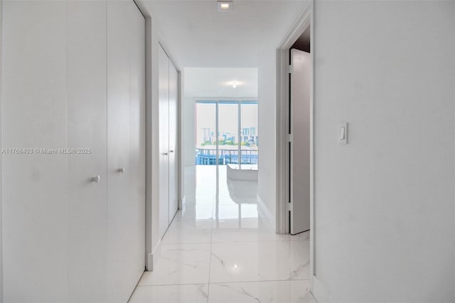 hallway featuring marble finish floor and baseboards