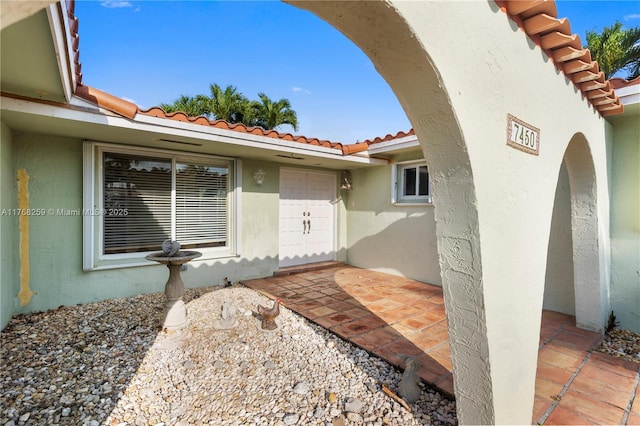 doorway to property with a tiled roof and stucco siding