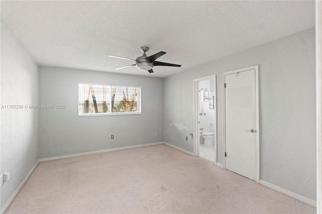 unfurnished bedroom featuring baseboards, carpet floors, ensuite bath, and a textured ceiling