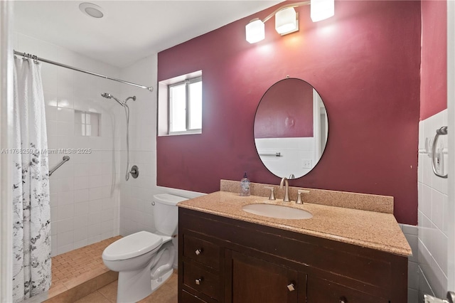 bathroom with toilet, vanity, tile patterned flooring, and tiled shower