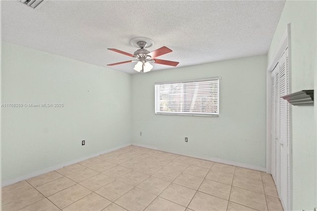 empty room with a textured ceiling, visible vents, baseboards, a ceiling fan, and light tile patterned floors