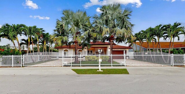 view of front of house featuring driveway, a fenced front yard, a gate, and stucco siding