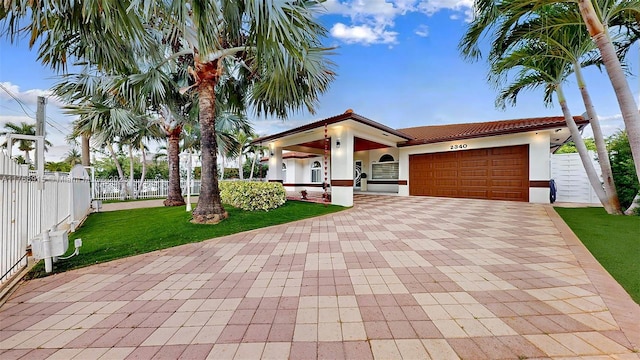 mediterranean / spanish-style home with a tile roof, a garage, fence, and stucco siding