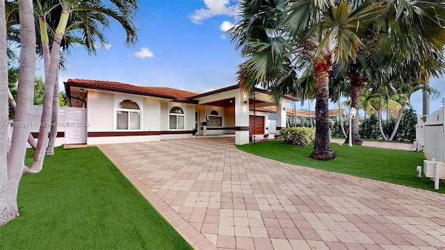 mediterranean / spanish-style house with a tile roof, stucco siding, and a front lawn