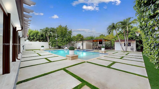 view of pool featuring a storage shed, a patio, a fenced in pool, a fenced backyard, and an outdoor structure