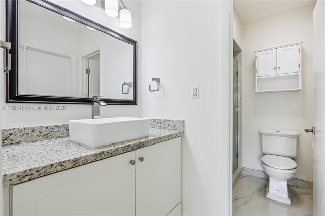 bathroom with a stall shower, toilet, vanity, marble finish floor, and baseboards