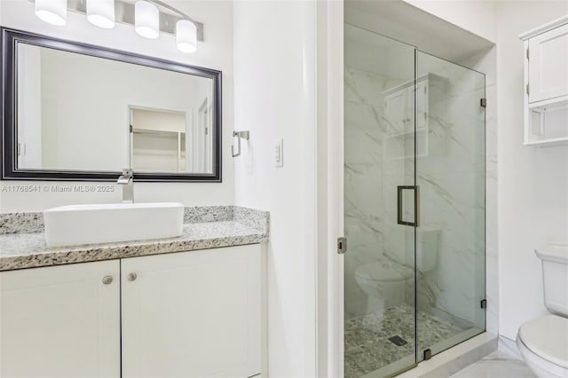 bathroom with a marble finish shower, marble finish floor, toilet, and vanity