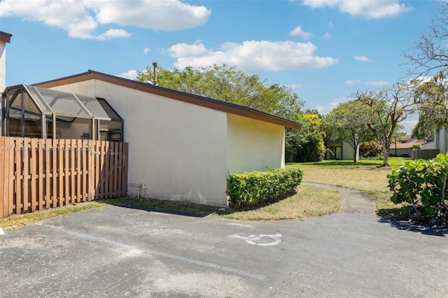 view of side of home featuring a lanai, stucco siding, and a lawn