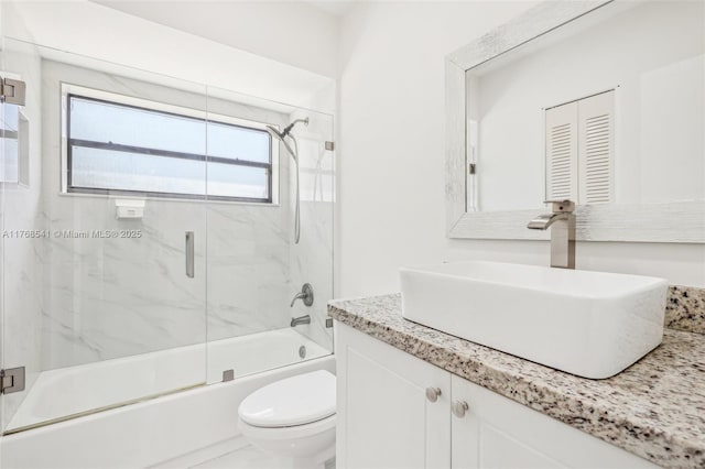 bathroom featuring toilet, shower / bath combination with glass door, and vanity