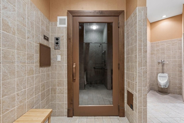 bathroom with tile walls, visible vents, tile patterned flooring, and a stall shower