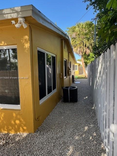 1025 NE 3rd Ave, Fort Lauderdale, FL 33304 - view of property exterior with stucco siding, central AC, fence, and a patio