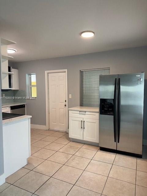 1025 NE 3rd Ave, Fort Lauderdale, FL 33304 - kitchen with light countertops, white cabinets, light tile patterned flooring, and stainless steel refrigerator with ice dispenser