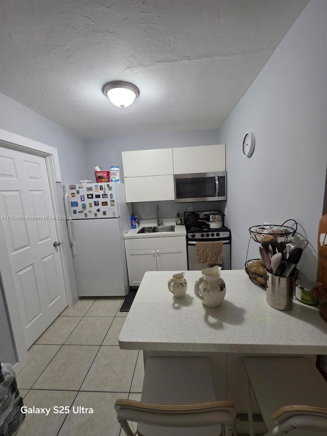 1025 NE 3rd Ave, Fort Lauderdale, FL 33304 - kitchen with a sink, a textured ceiling, a peninsula, stainless steel appliances, and white cabinets