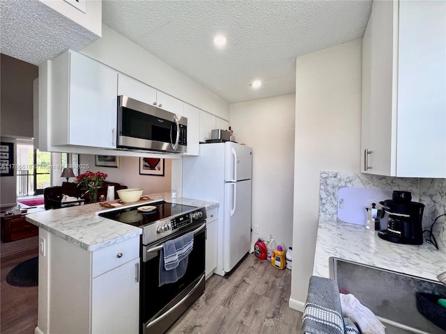 1460 Jefferson Dr Unit H, Homestead, FL 33034 - kitchen featuring light countertops, light wood-type flooring, decorative backsplash, white cabinets, and appliances with stainless steel finishes