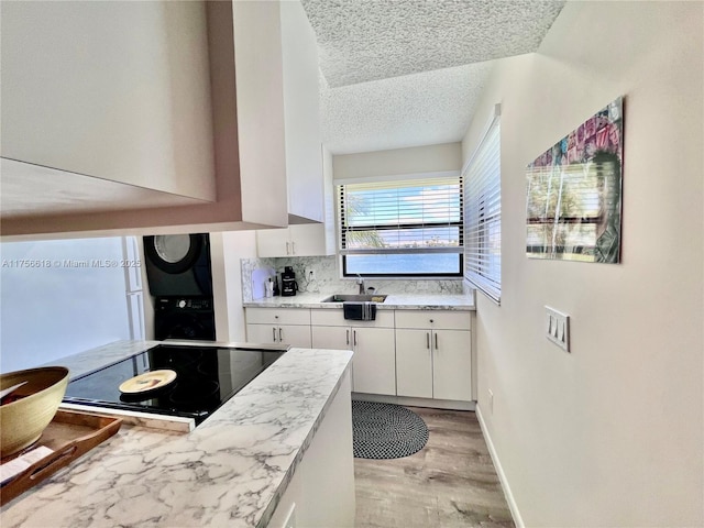 1460 Jefferson Dr Unit H, Homestead, FL 33034 - kitchen featuring black electric cooktop, white cabinetry, stacked washing maching and dryer, a textured ceiling, and a sink