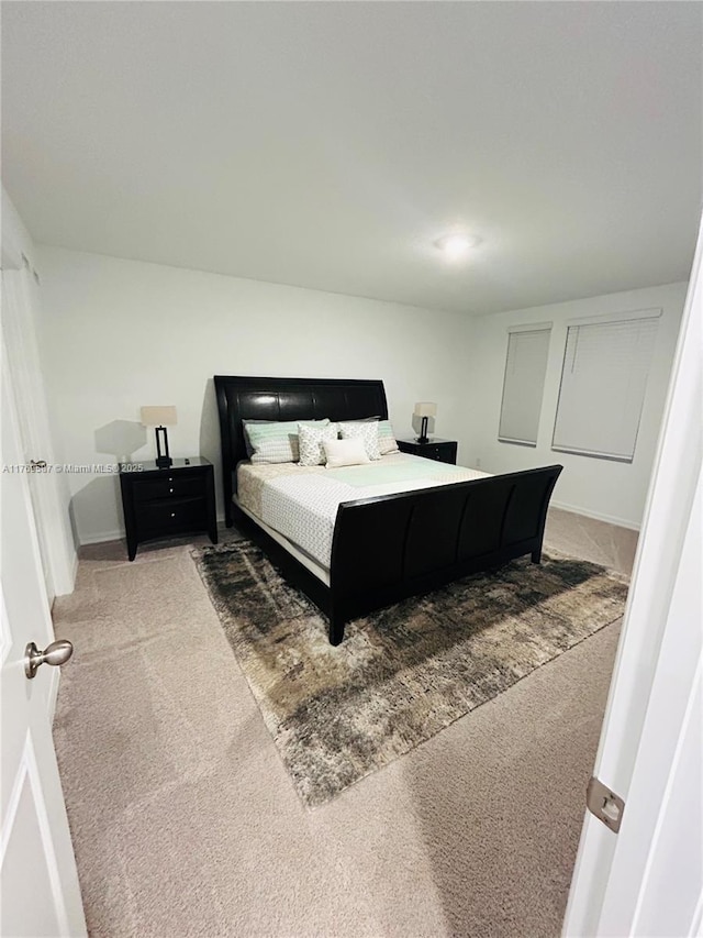 bedroom with baseboards and light colored carpet