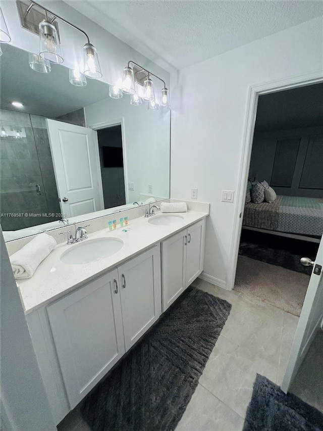 full bath featuring double vanity, a textured ceiling, a sink, and a stall shower
