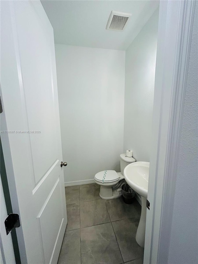 bathroom with tile patterned flooring, toilet, baseboards, and visible vents
