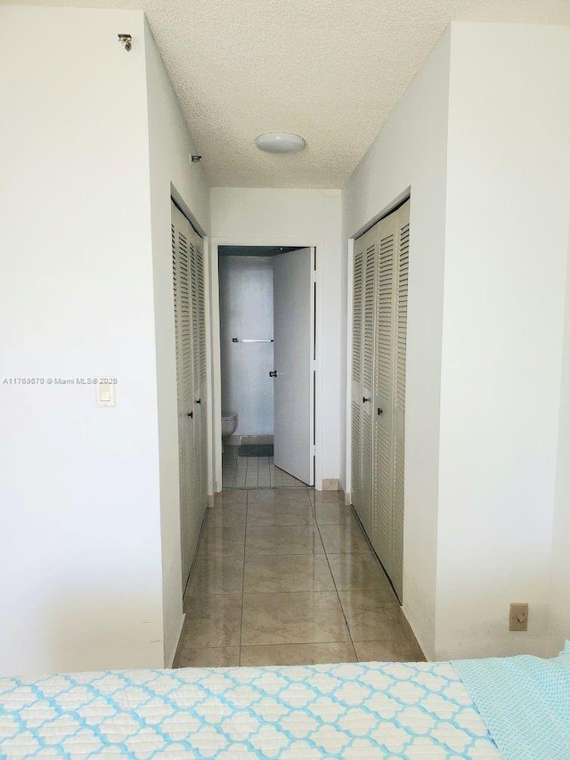 hall featuring a textured ceiling and light tile patterned floors