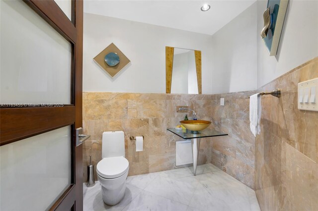 4000 Island Blvd Unit Ph6, Aventura, FL 33160 - half bathroom featuring tile walls, wainscoting, toilet, and a sink