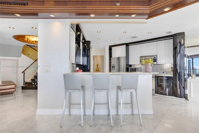 4000 Island Blvd Unit Ph6, Aventura, FL 33160 - kitchen with white cabinetry, a kitchen breakfast bar, modern cabinets, stainless steel appliances, and decorative backsplash