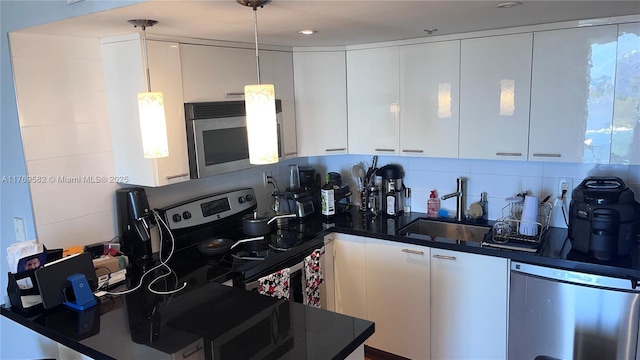 kitchen featuring stainless steel appliances, a sink, dark countertops, and tasteful backsplash