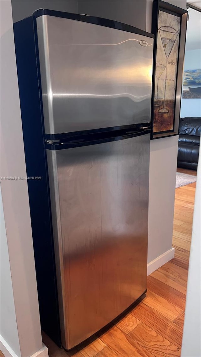 room details featuring baseboards, light wood-style floors, and freestanding refrigerator