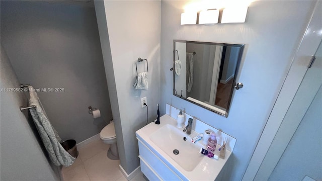 bathroom featuring baseboards, vanity, tile patterned flooring, and toilet