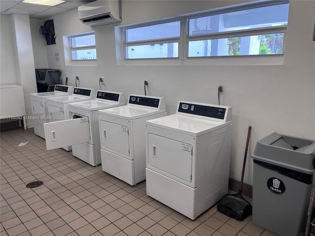 community laundry room featuring washer and clothes dryer, a wall mounted AC, and light tile patterned floors