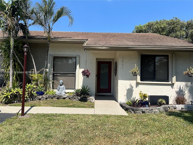 single story home featuring stucco siding, a front yard, and a shingled roof